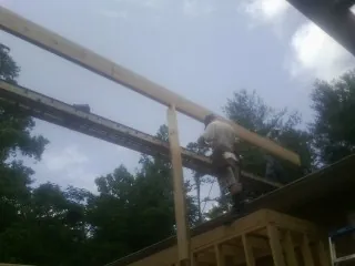 Carpenter setting a ridge beam over a new addition frame — Ice Dam Removal by Roofing Brothers in Prospect Park