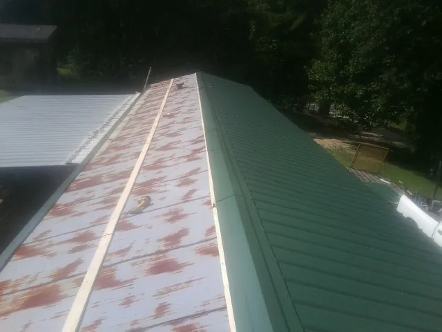 Old rusted panels beside newly installed green metal roofing — Wind Damage Roof Repair by Roofing Brothers in Prospect Park