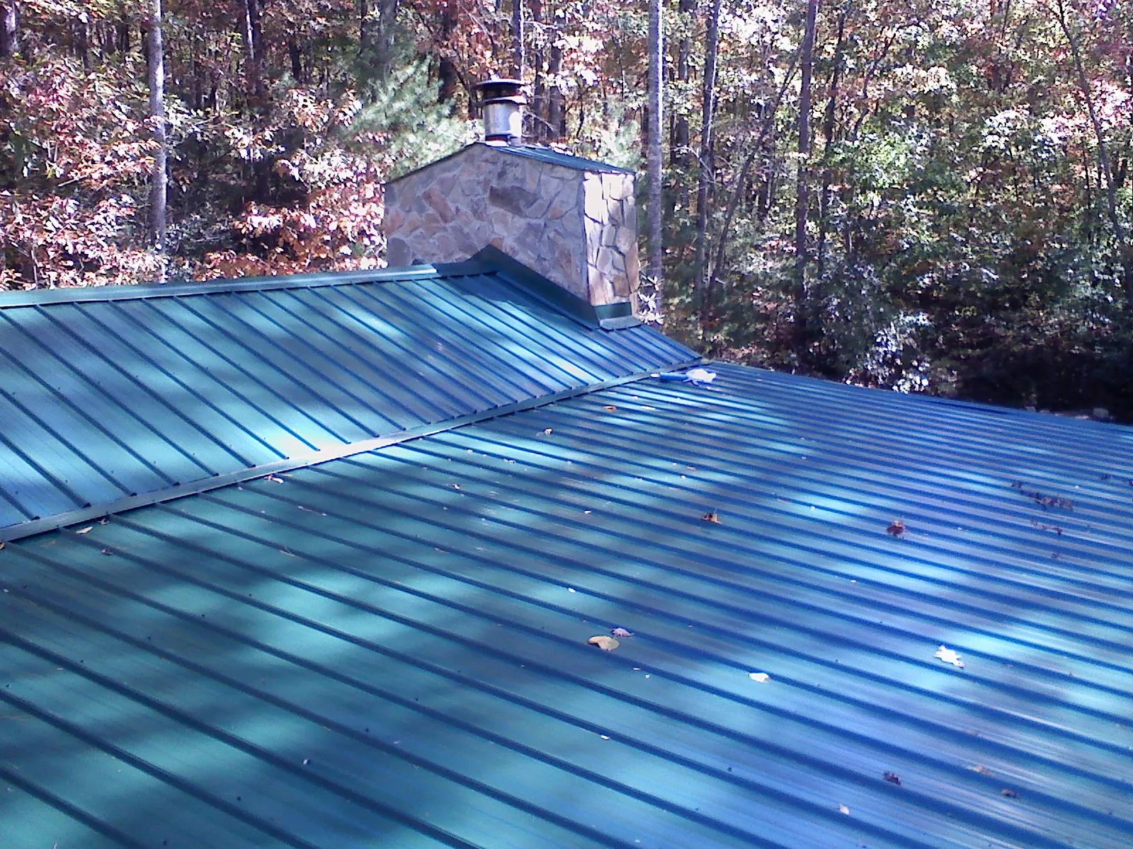 New green metal roof and stone chimney surrounded by autumn woods in Prospect Park