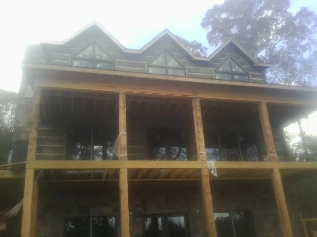 Dormers and porch framing on a large log home under construction — Roof Coating work by our crew in Prospect Park