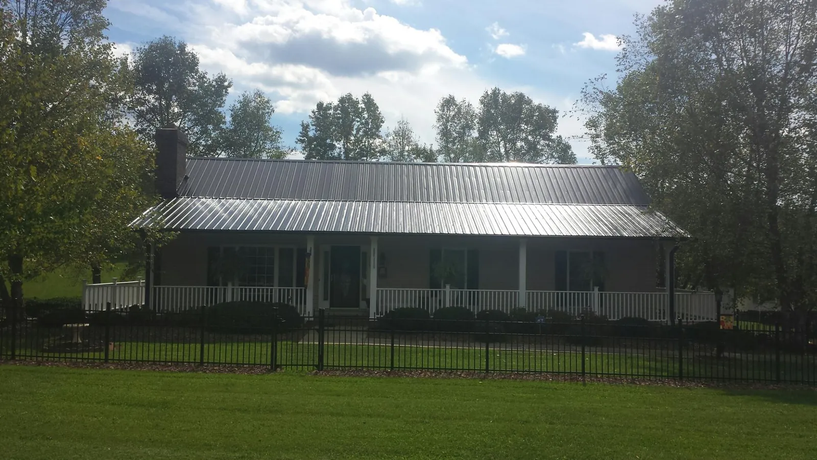 Gray metal roof on a brick ranch with a full width front porch — Gutter Guard Installation work by our crew in Prospect Park