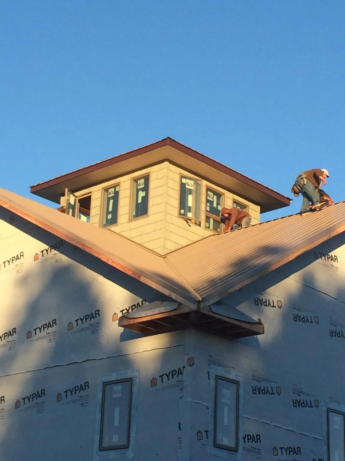 Roofers working around a rooftop cupola on a new metal roof at sunset — Roof Waterproofing in Prospect Park by Roofing Brothers